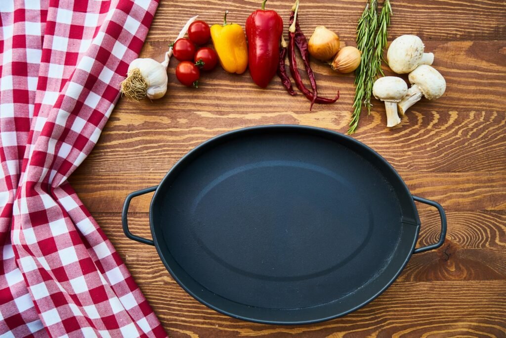 A raw cast iron skillet and an enameled cast iron pan shown side by side with cleaning tools