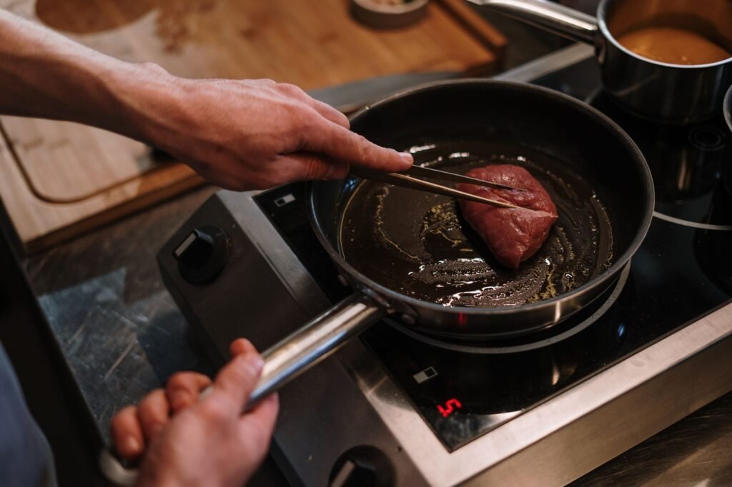 A modest apartment kitchen with three practical cookware pieces in use on the stove.