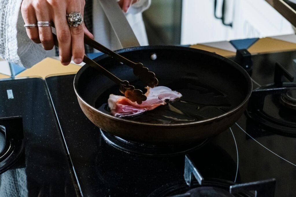 A stainless steel skillet heating on a stovetop with oil just starting to shimmer.