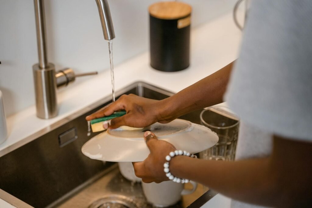 A stainless steel skillet being cleaned with baking soda paste and a soft sponge.