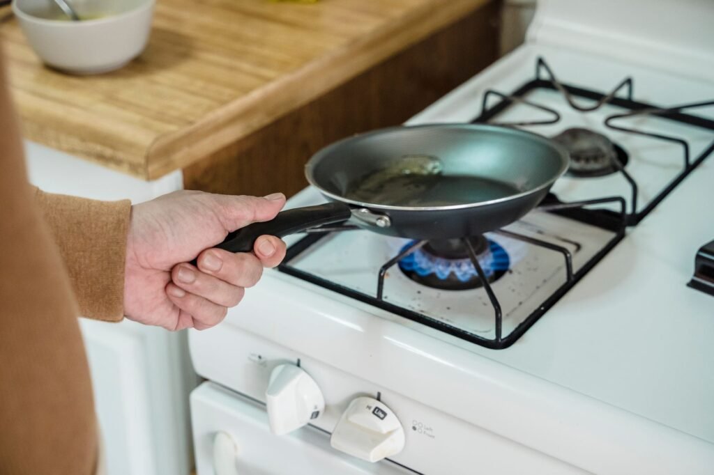 Calculator, receipts, cooking oil, and a frying pan on a kitchen counter